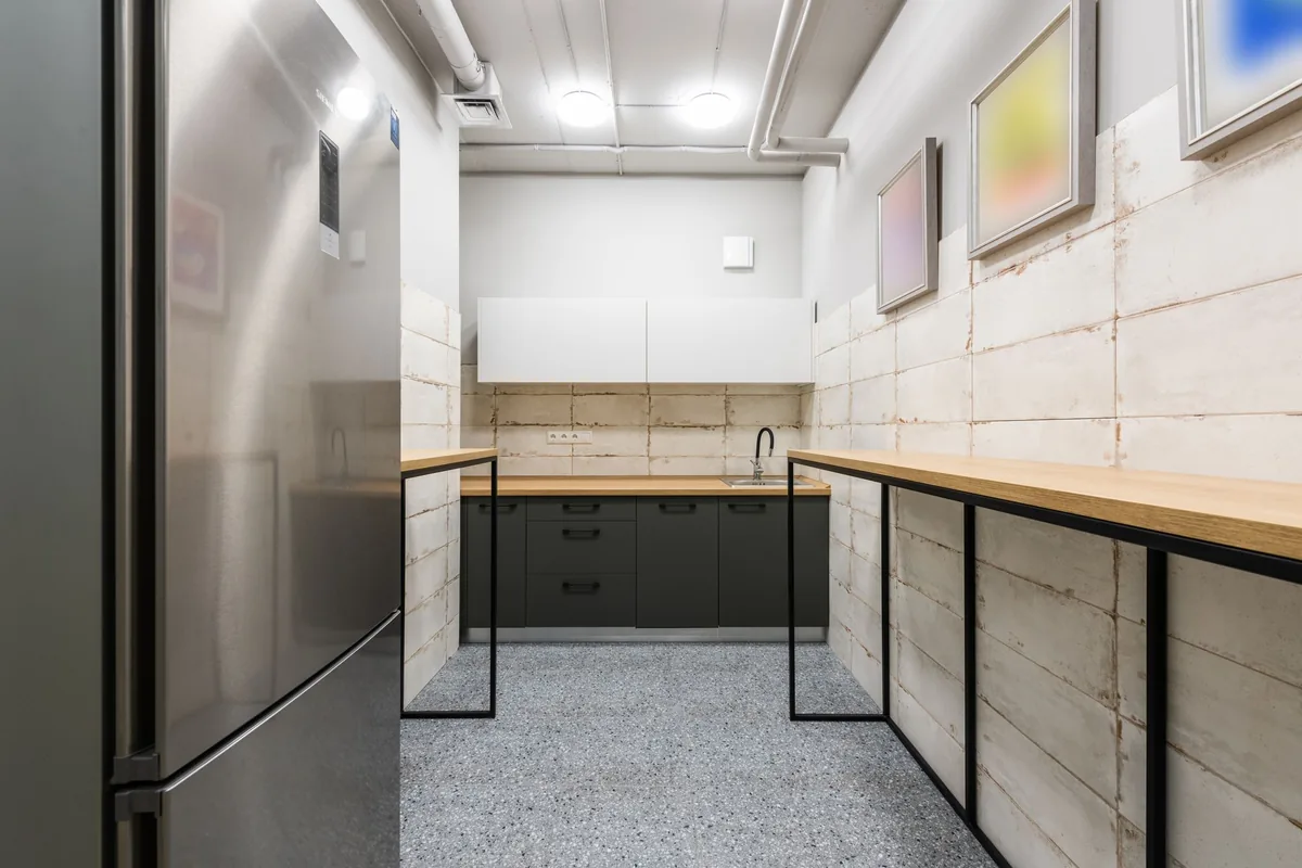A long office kitchen counter with a tall refrigerator