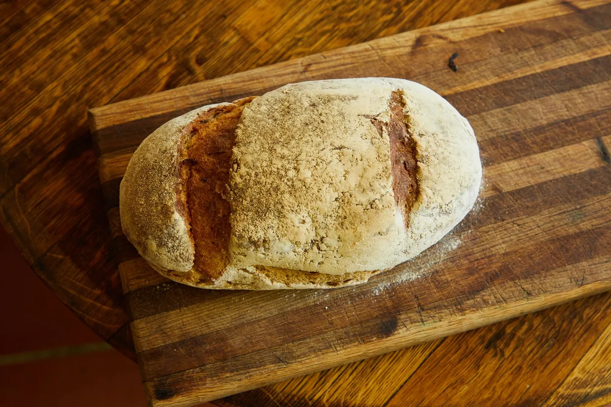 An oval loaf of bread on a wooden board
