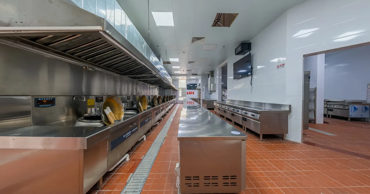 A long stainless commercial kitchen with prep stations