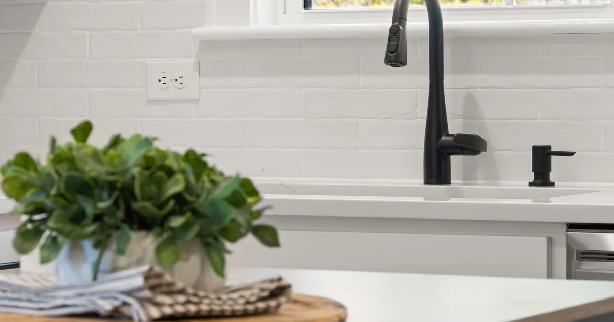 A matte black faucet over a white sink in a bright kitchen