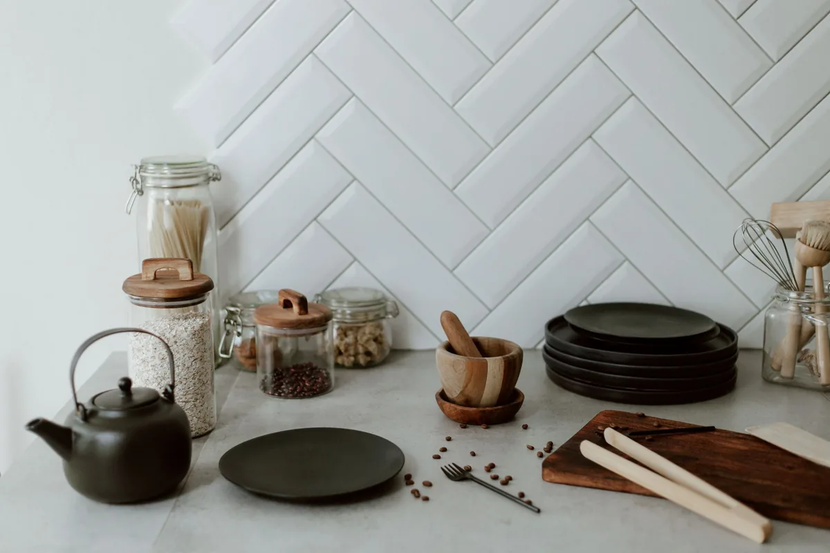 A matte kettle next to a bowl of roasted coffee beans on a pale kitchen worktop