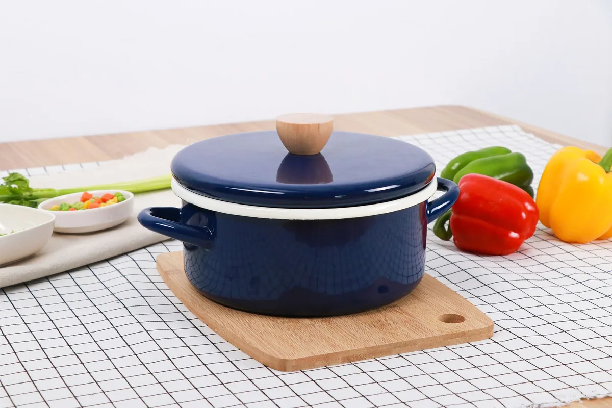 A navy enamelled pot with a wooden knob lid on a checked tablecloth