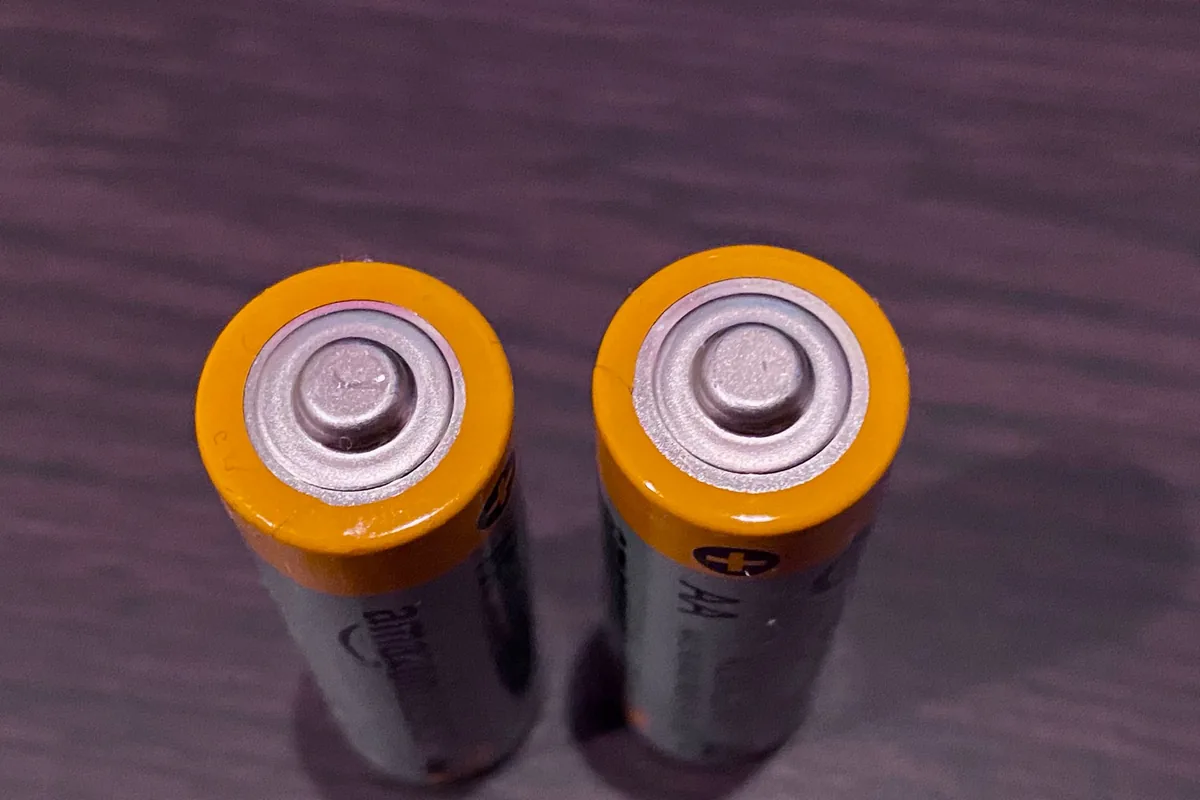 A neat row of AA batteries lying on a white surface