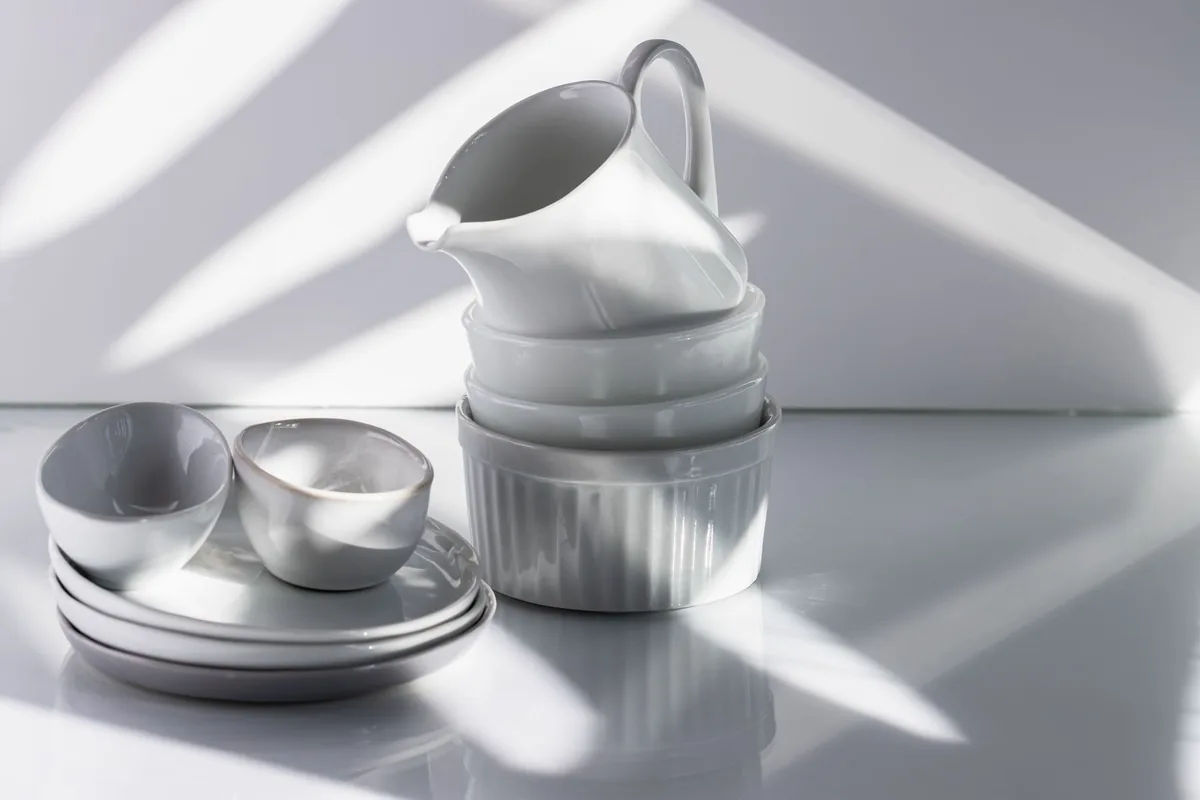 A neat stack of clean white plates on a light kitchen shelf