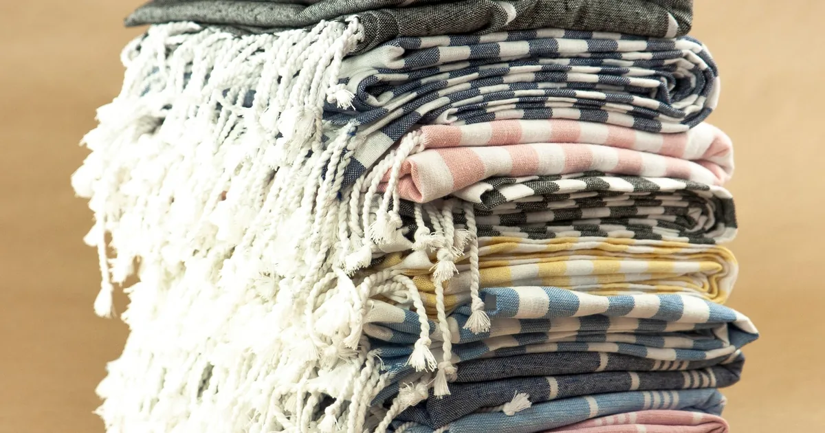A neat stack of folded cotton kitchen towels on a bright kitchen worktop