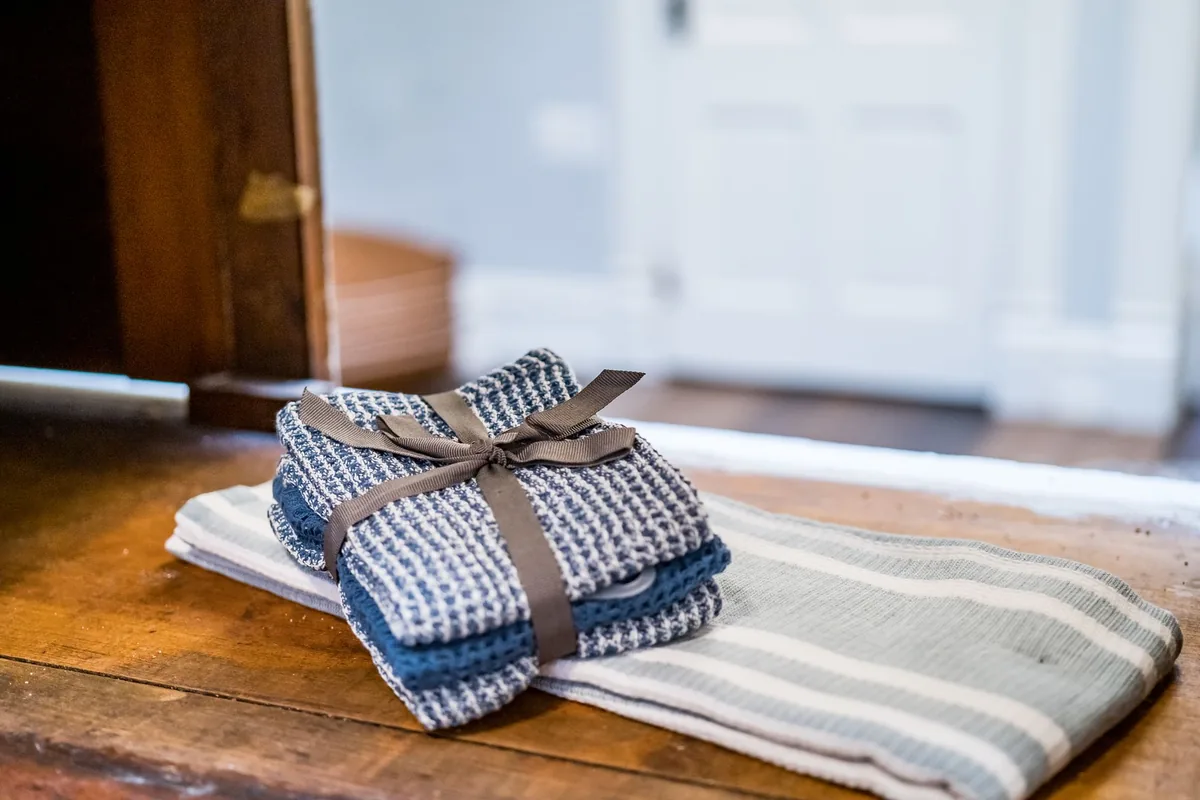 Folded blue dish towels tied with a ribbon on a wooden table