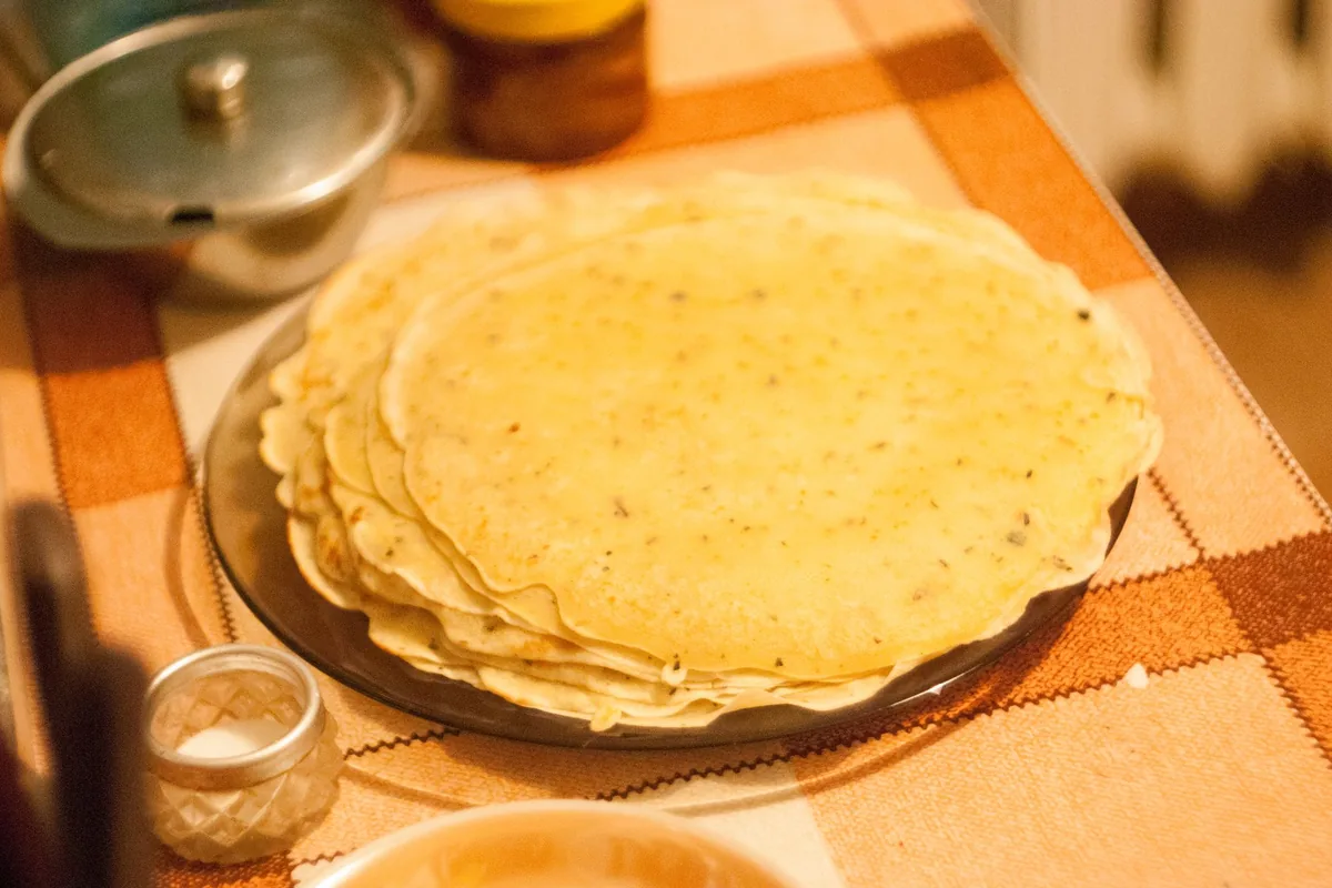 A neat stack of warm flour tortillas on a wooden board in daylight