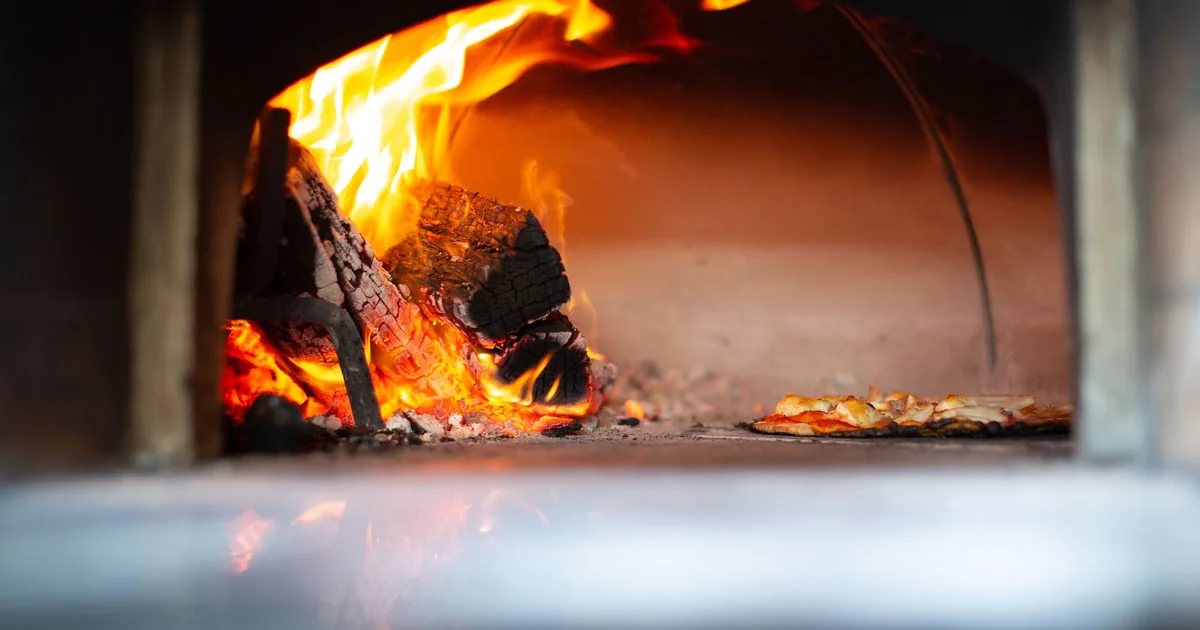 A wood fire burning inside a pizza oven