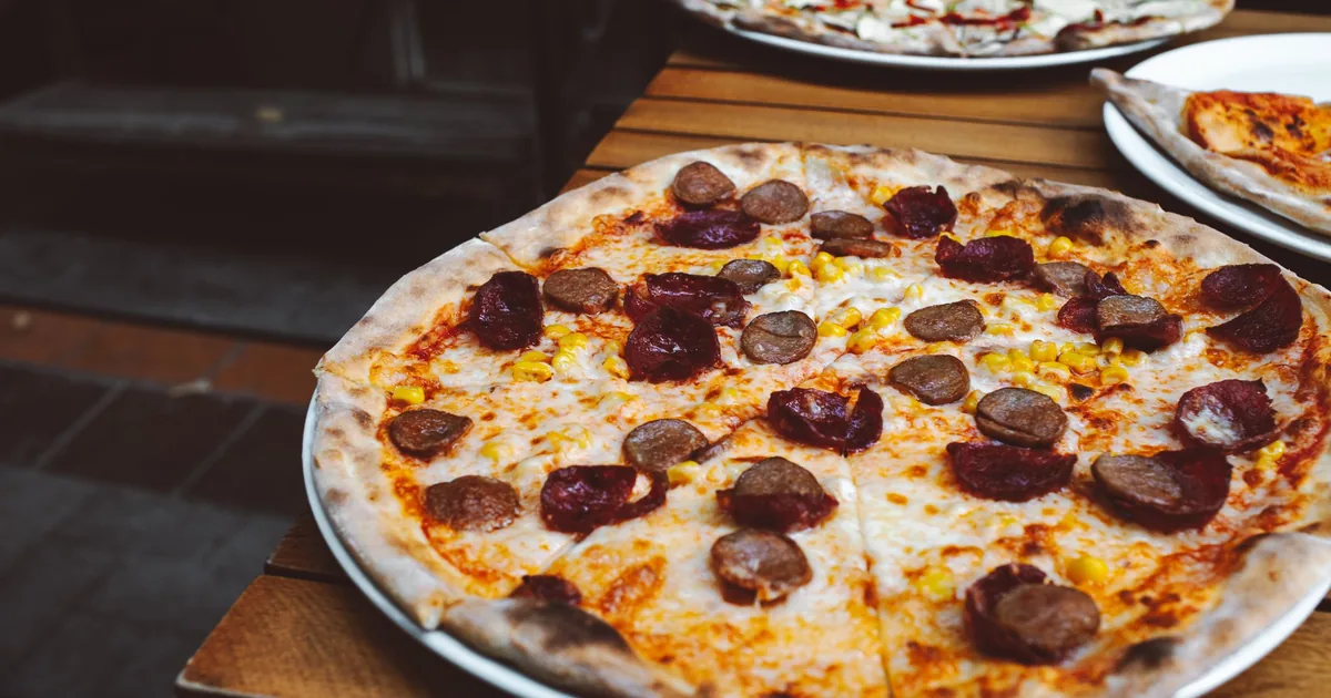 A pepperoni pizza served on an outdoor table