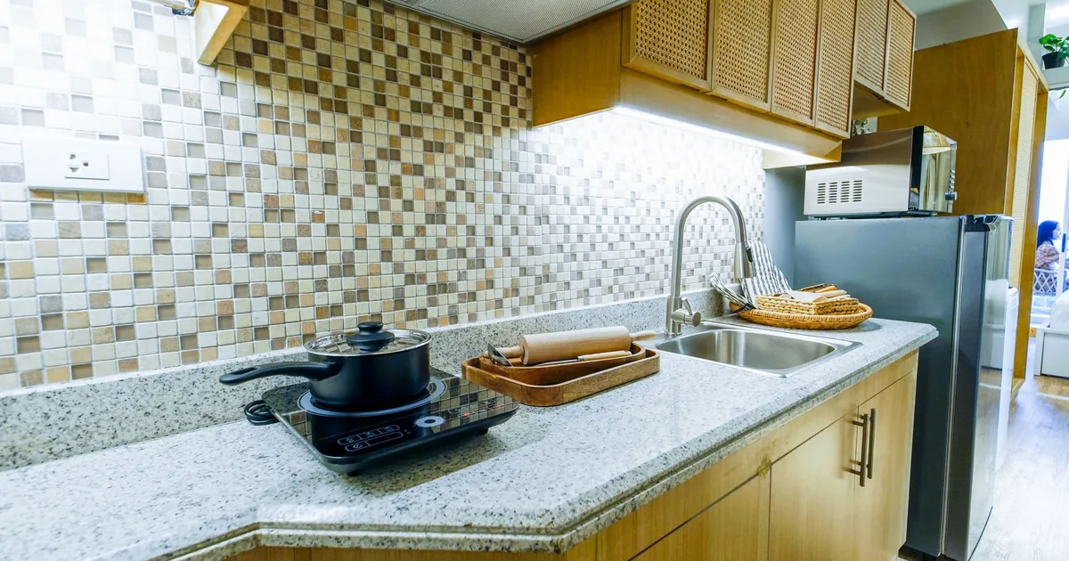 A pot on a smooth cooktop in a kitchen with a tiled backsplash