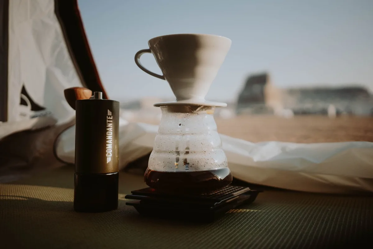A pour-over dripper and glass server on a table by a window