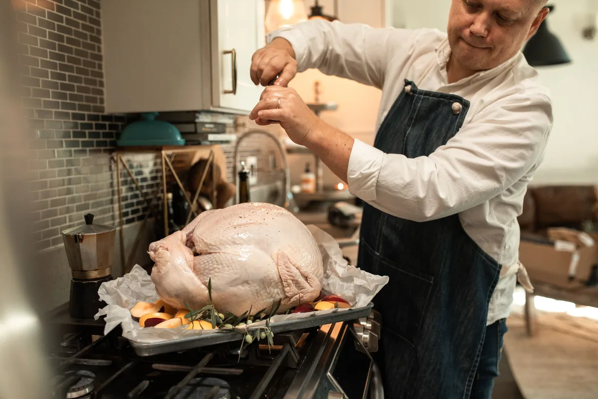 A roast turkey in a pan beside green beans and mashed potatoes