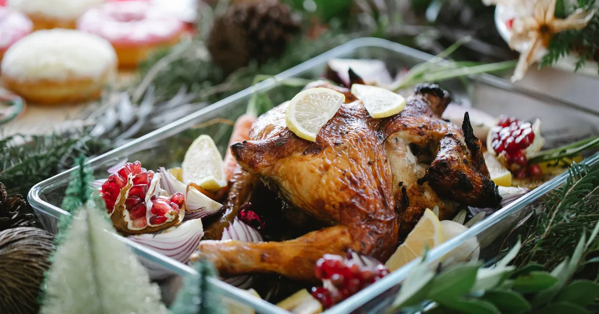 A roasted turkey in a glass baking dish surrounded by festive decorations