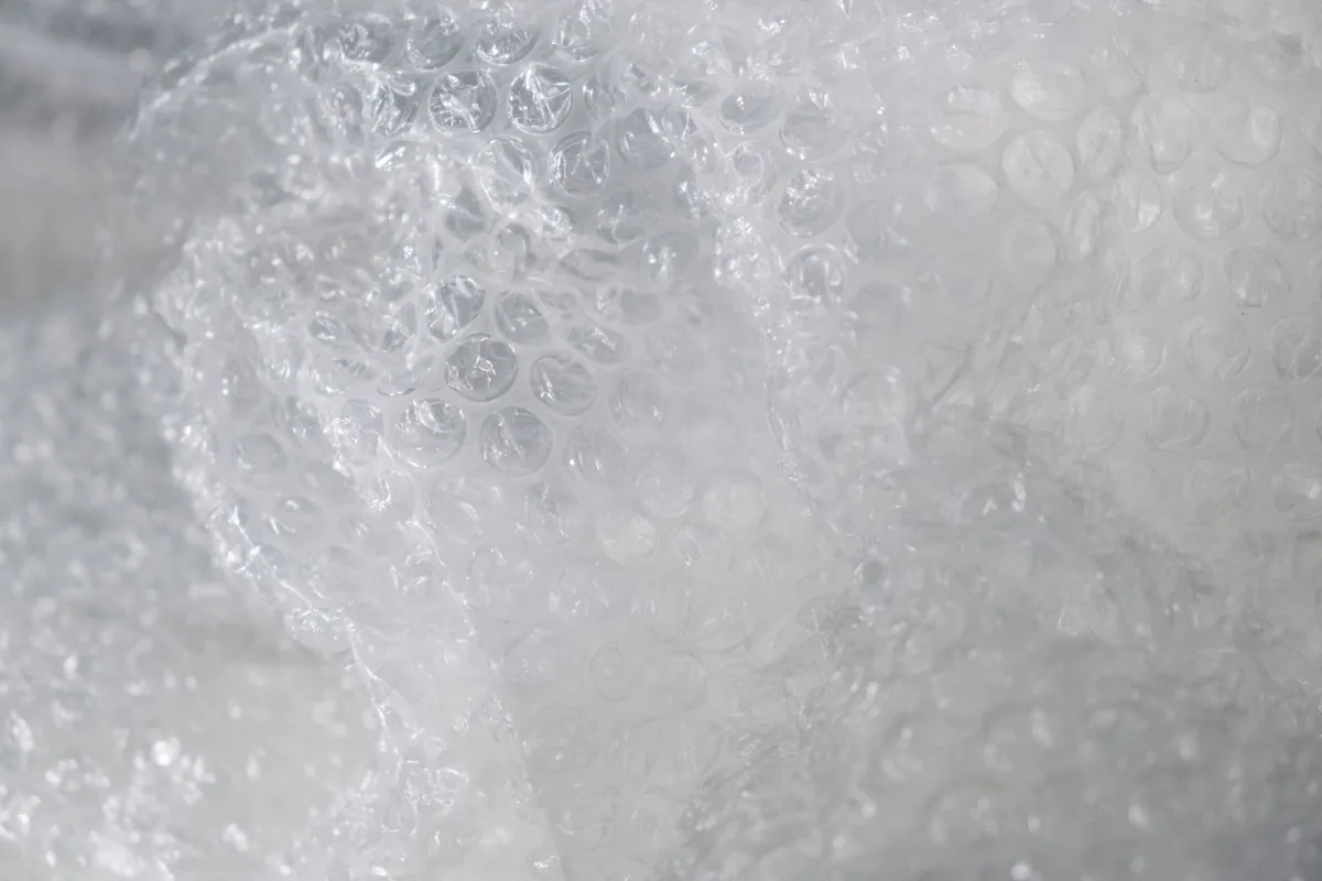 A roll of clear plastic film resting on a plain white surface
