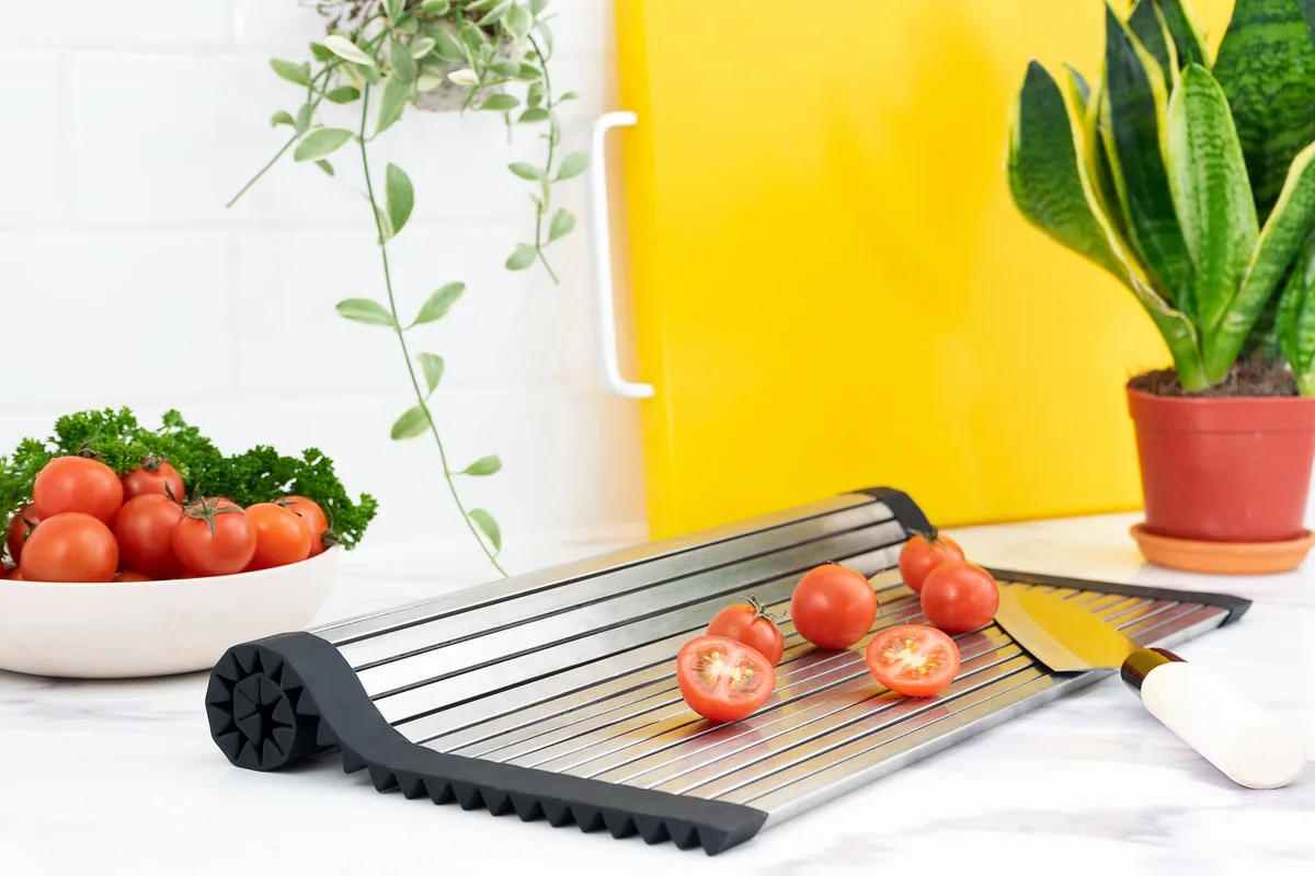 A roll-up drying rack holding tomatoes over a sink