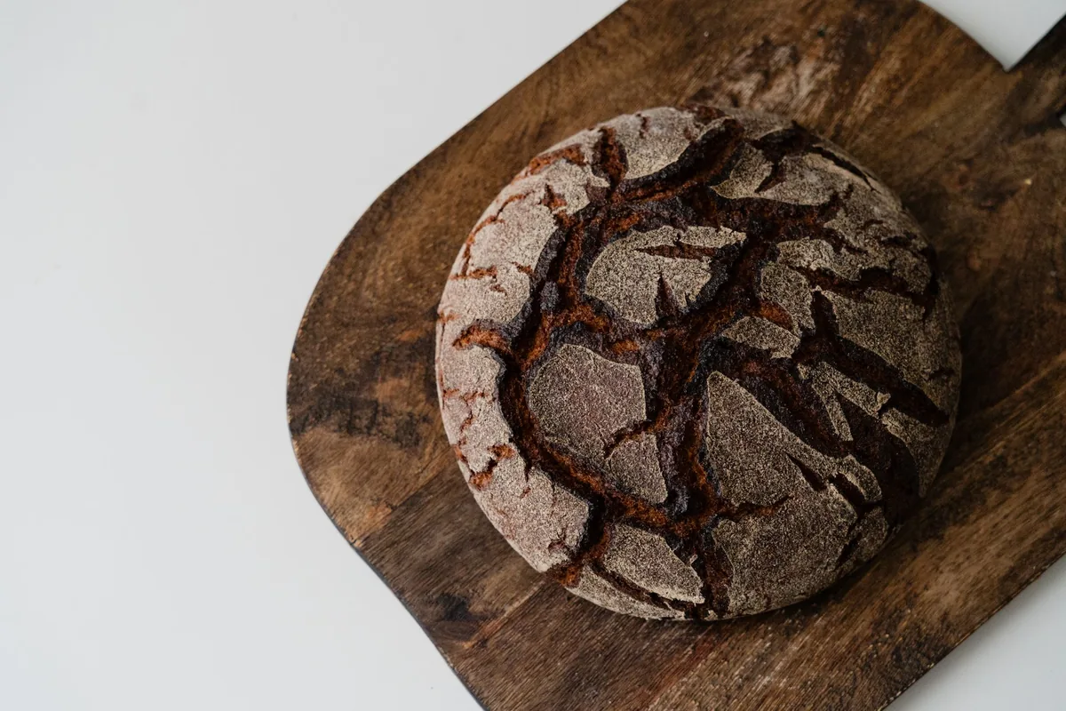 A round crusty bread loaf on a wooden board in soft daylight