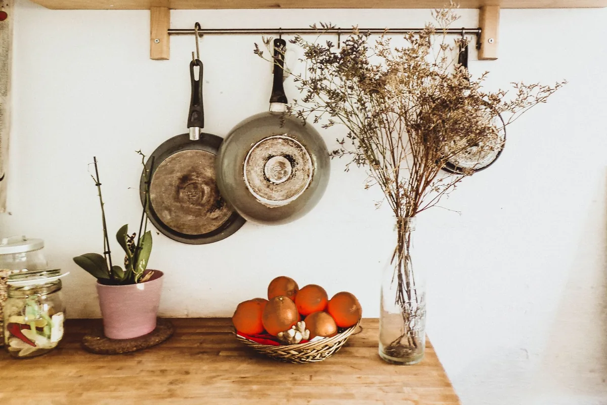 A row of frying pans of different sizes hanging from a rail in a bright kitchen