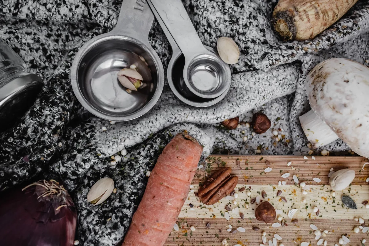 A row of metal measuring spoons holding different ground spices on a white counter