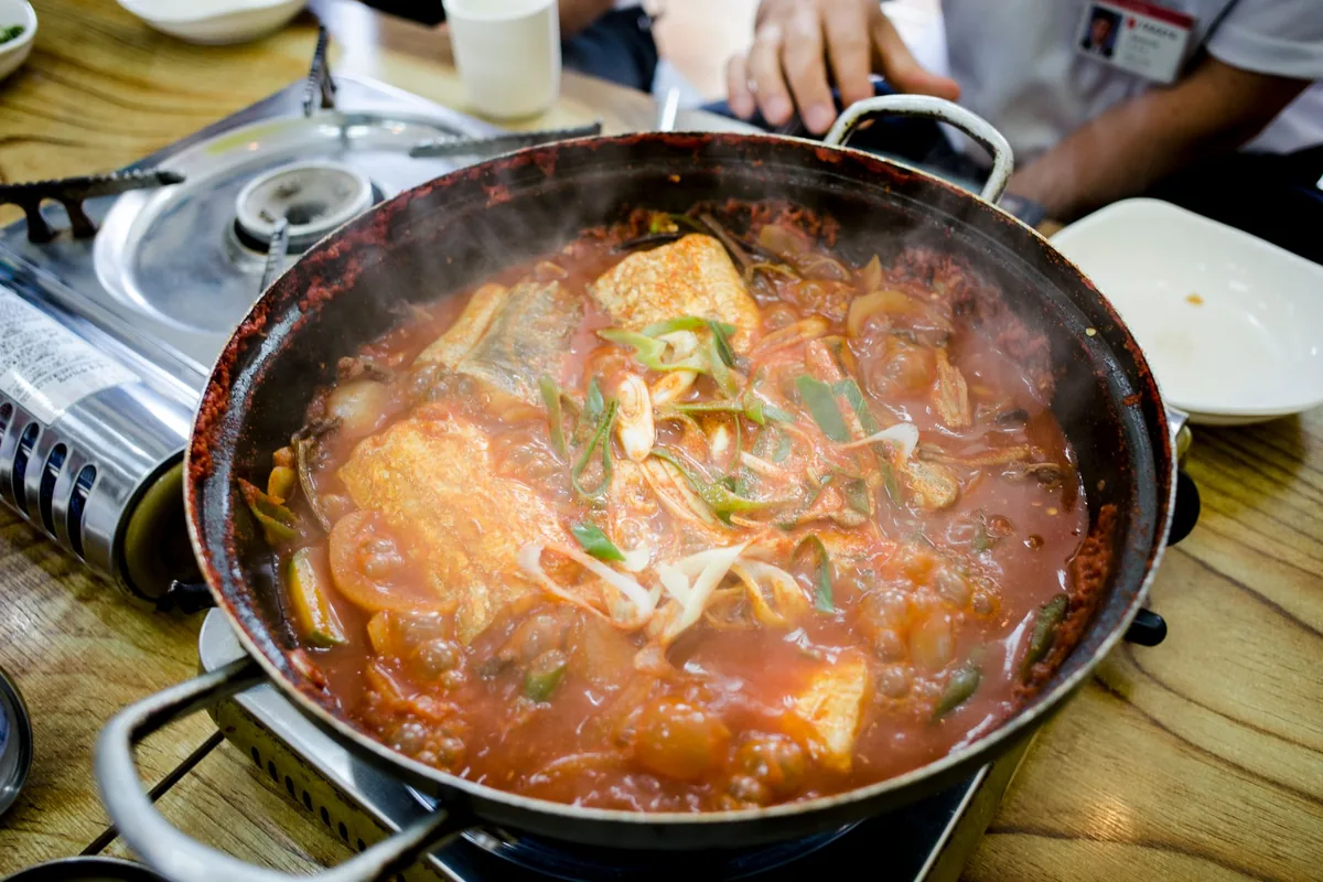 A simmering braise visible through a clear glass pan lid