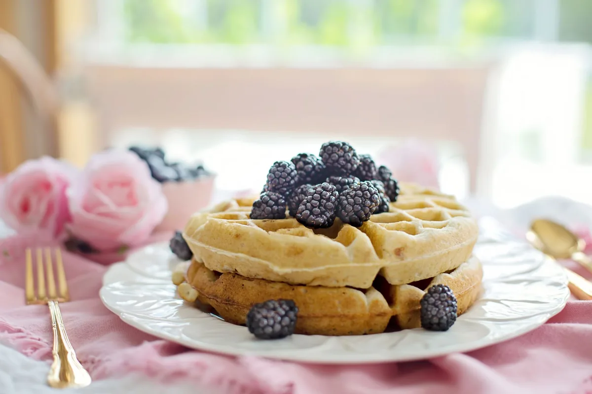 A single golden waffle with deep square pockets on a plain white plate