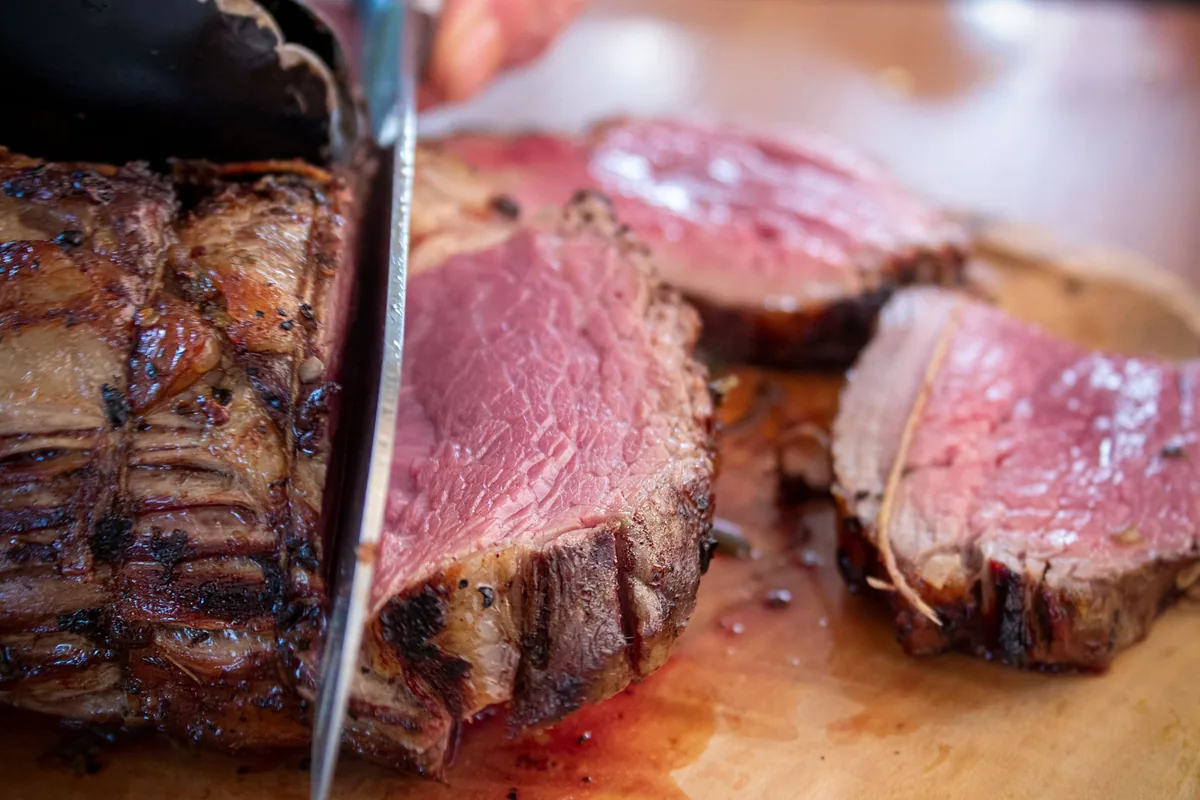 A sliced beef roast with a pink centre on a carving board