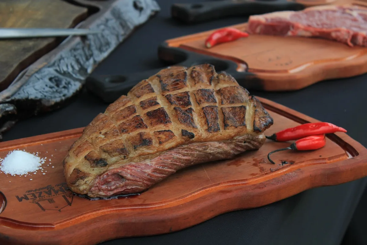 A sliced steak with dark grill marks resting on a wooden board