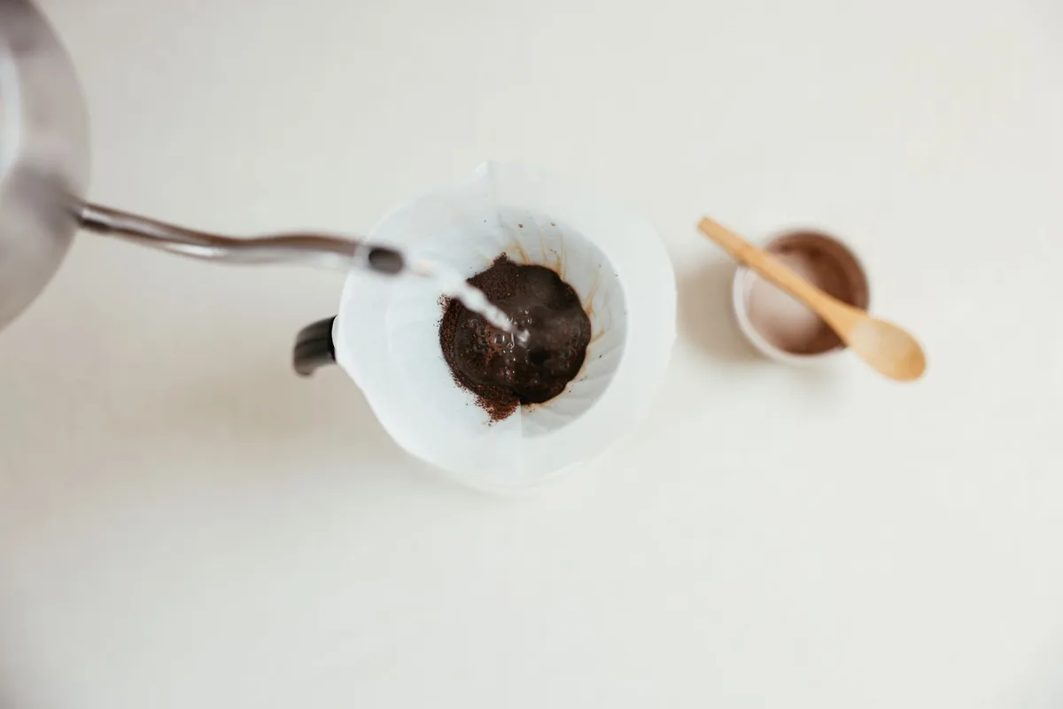 Hot water poured from a gooseneck kettle into a coffee dripper
