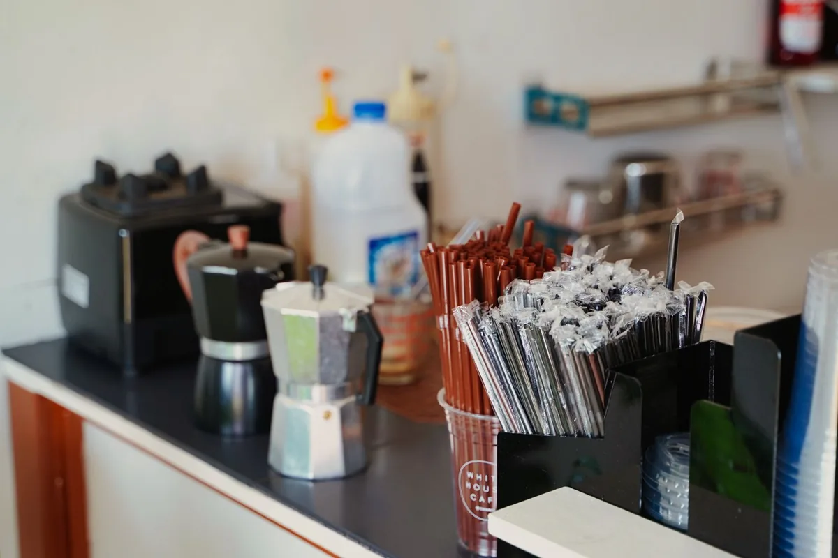 A small coffee station on a counter with cups and supplies
