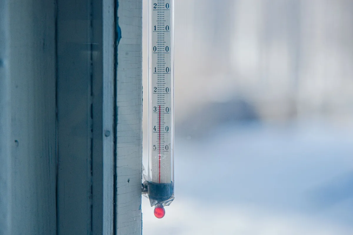 A glass thermometer mounted beside a frosty window
