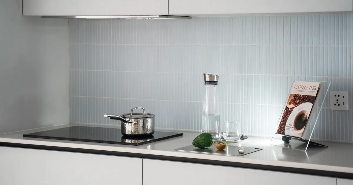 A small pot on a flush induction cooktop in a bright white kitchen