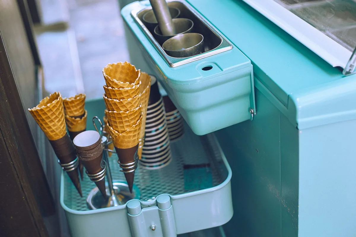 A small retro ice cream machine with cones beside it