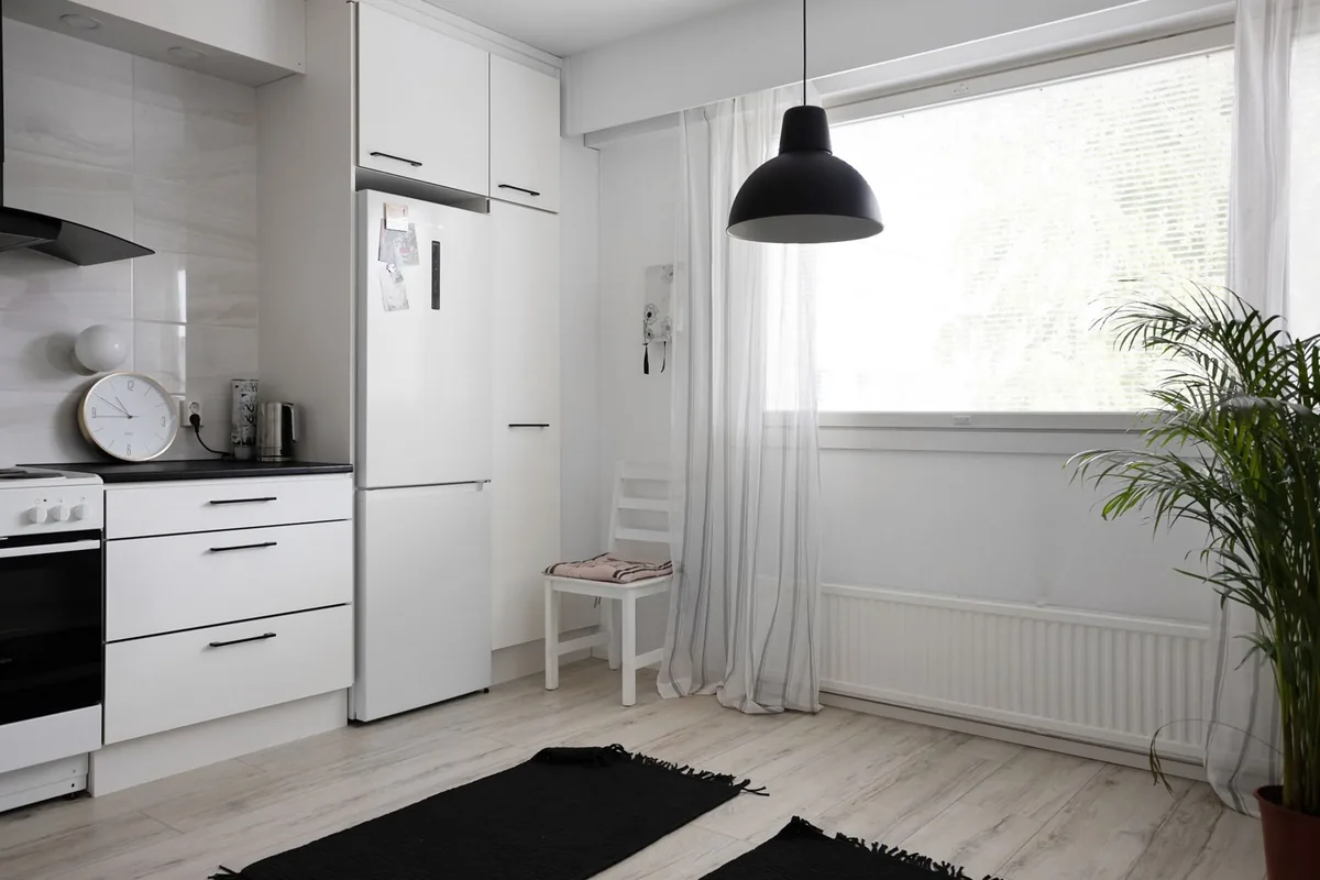 A small white kitchen with a refrigerator by the window