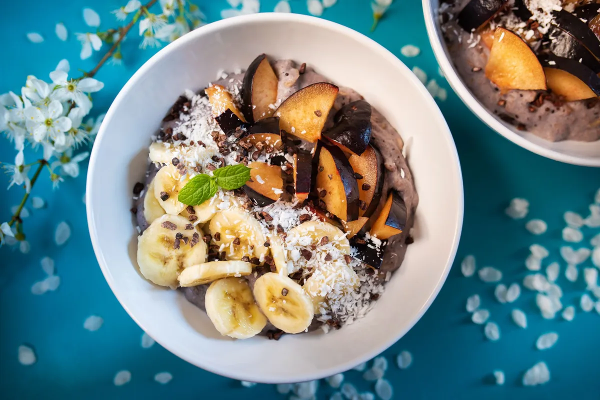 A smoothie bowl topped with banana slices, coconut flakes and seeds, seen from above