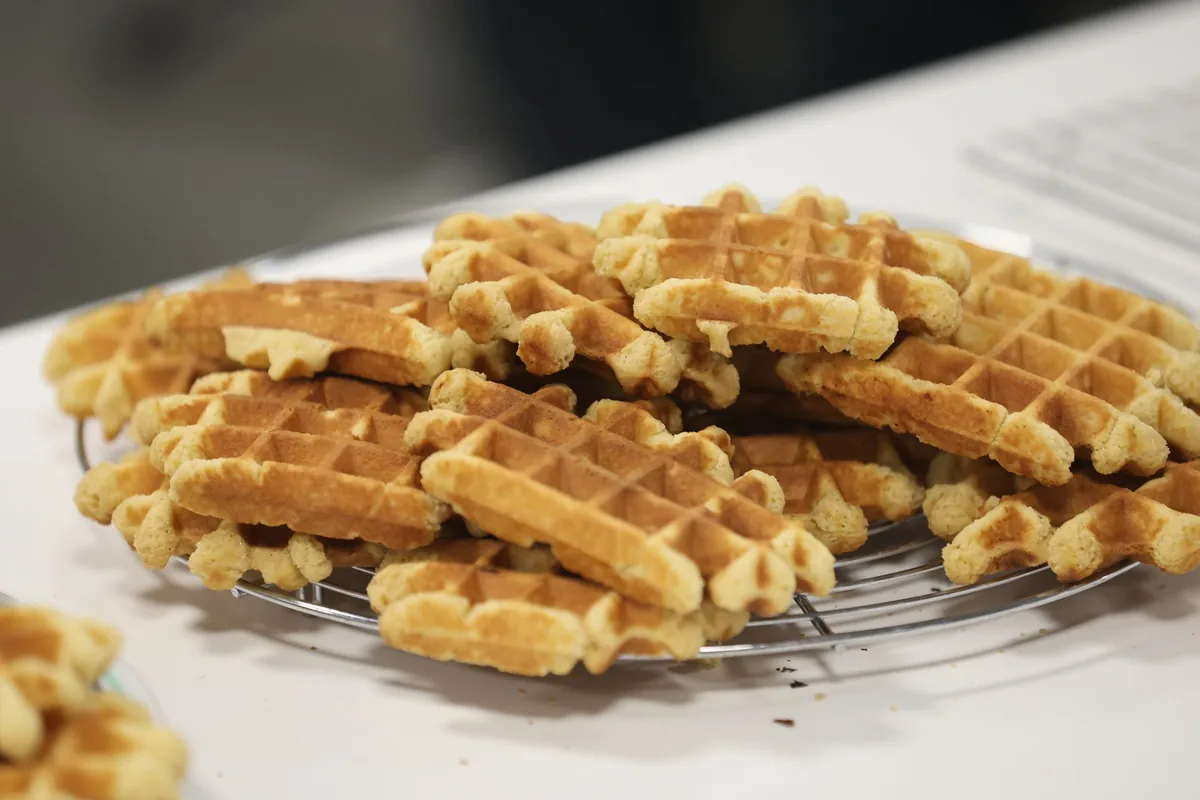 A stack of crisp square waffles on a wooden board on a light kitchen counter