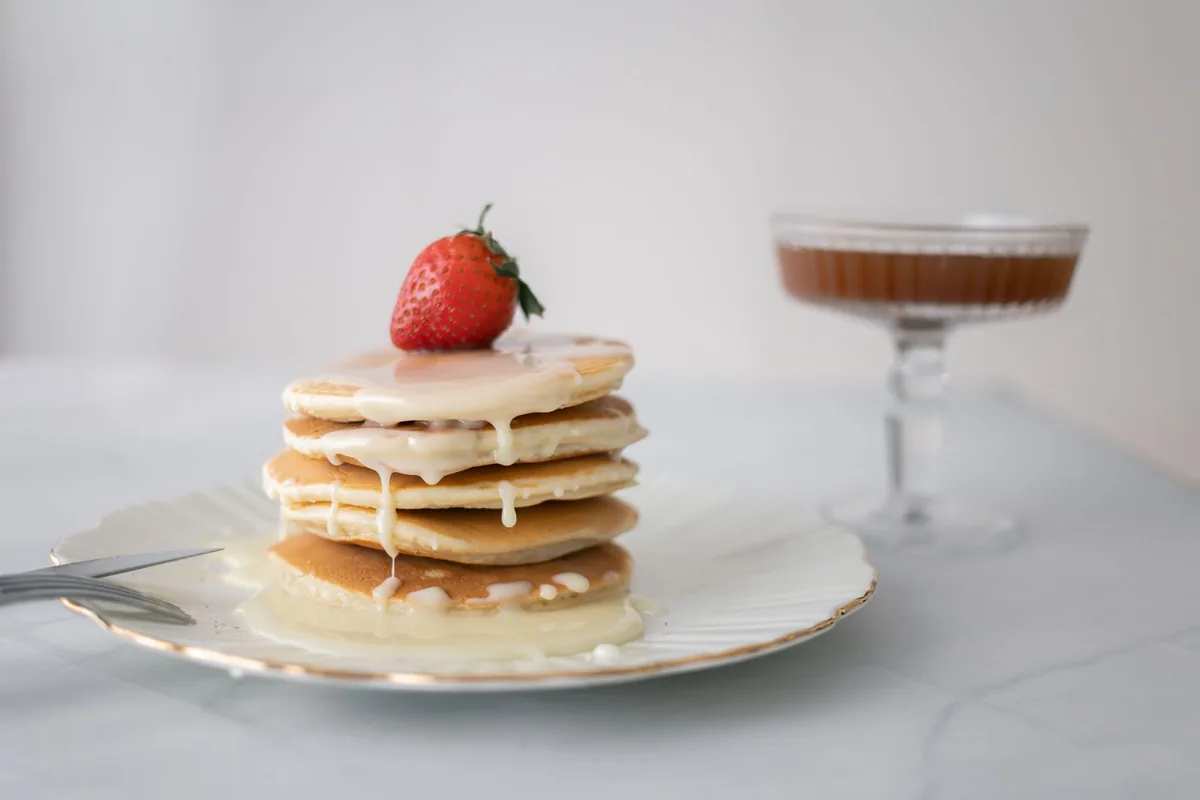 A stack of pancakes topped with a strawberry