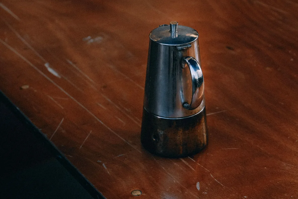 A stainless steel coffee pot on a wooden table