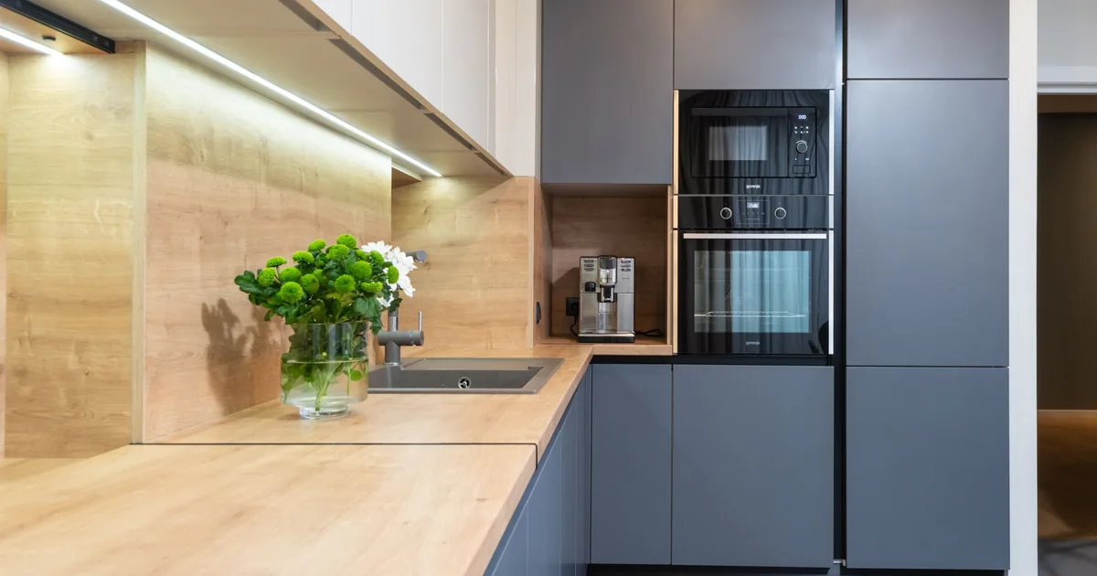 A modern kitchen with a built-in microwave and oven in a tall cabinet