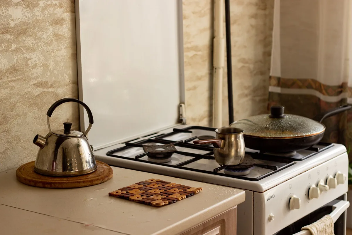 A stainless steel kettle heating on a gas hob