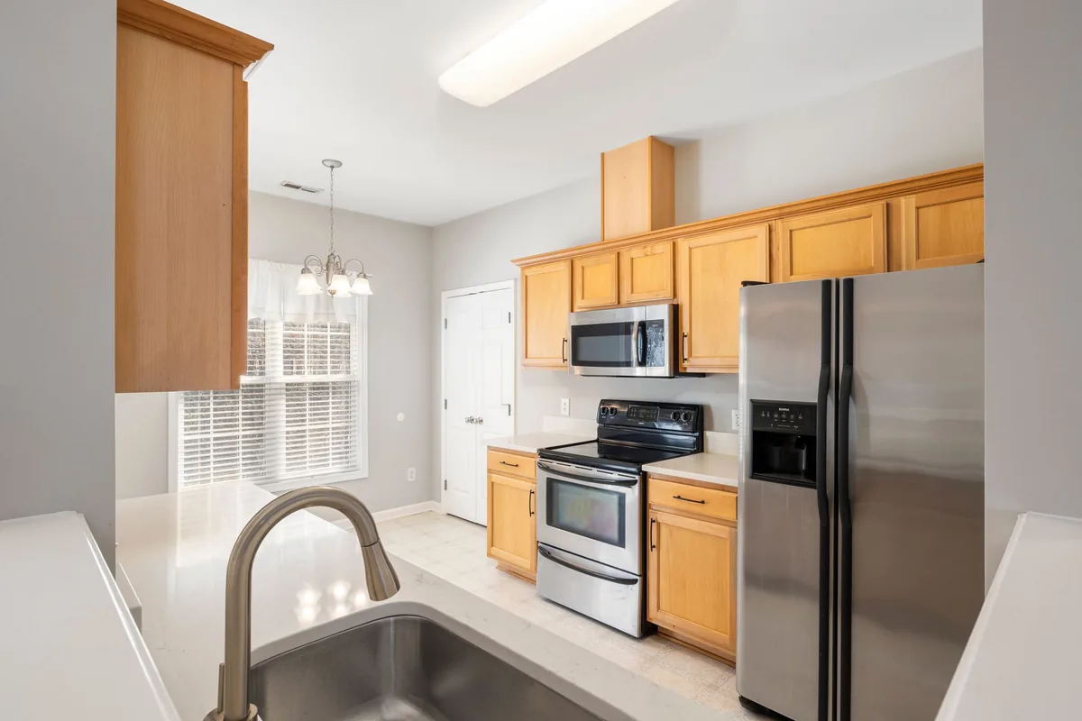 A stainless steel kitchen faucet arching over a clean empty sink