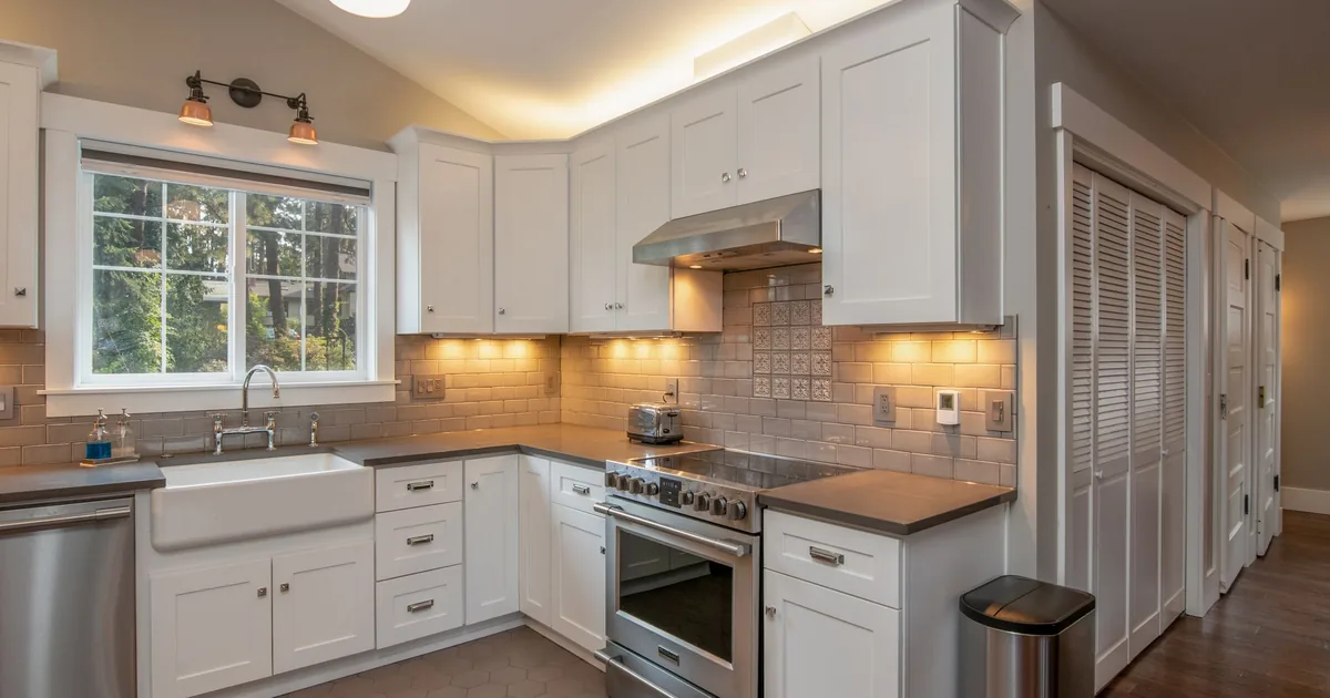 A stainless steel toaster oven on a light kitchen worktop with its door closed and a tray inside