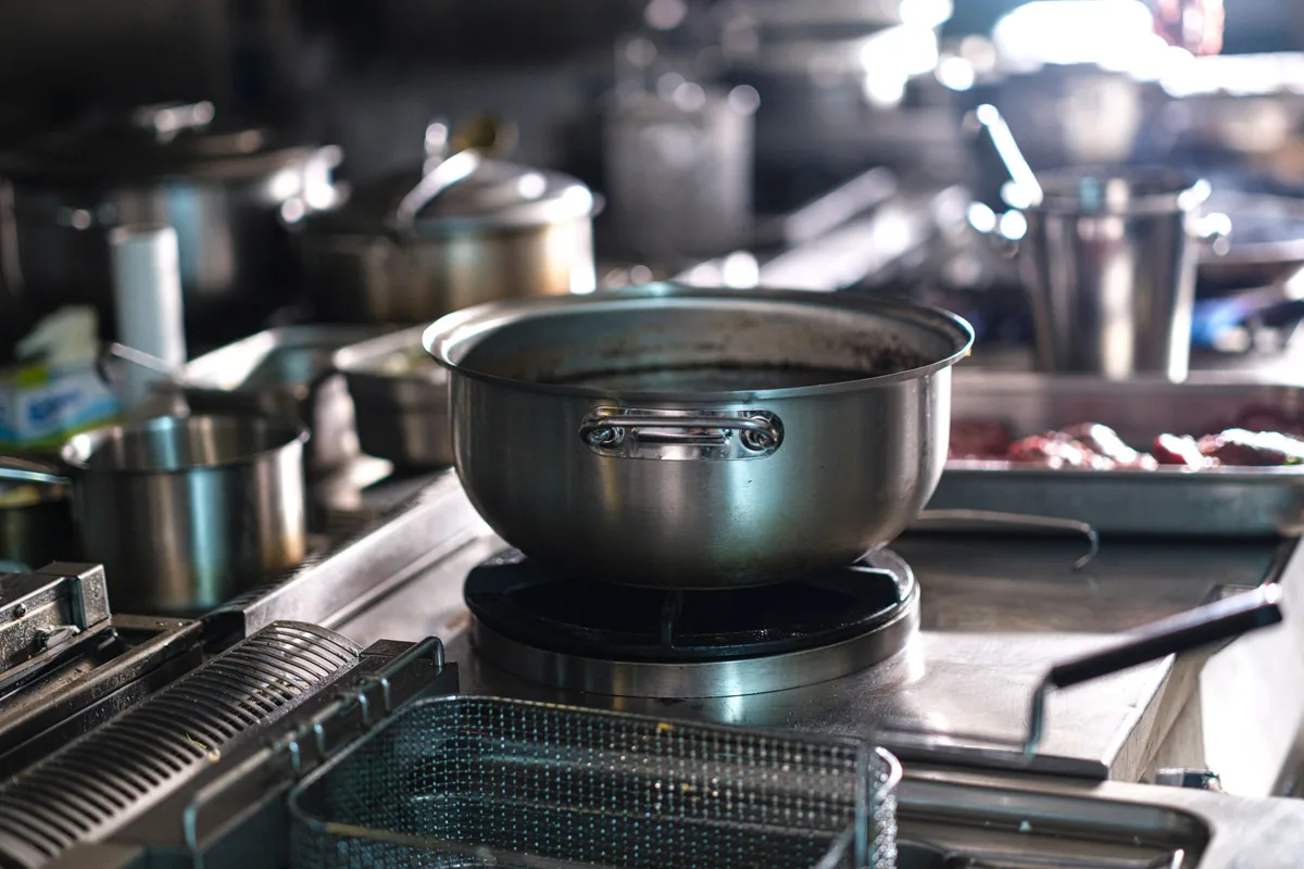 A steel pot on a stovetop in a busy kitchen