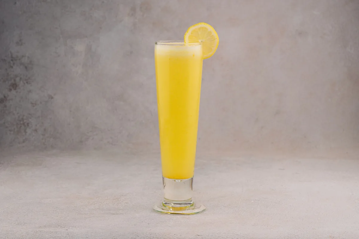 A tall glass of chilled lemon drink on a grey surface