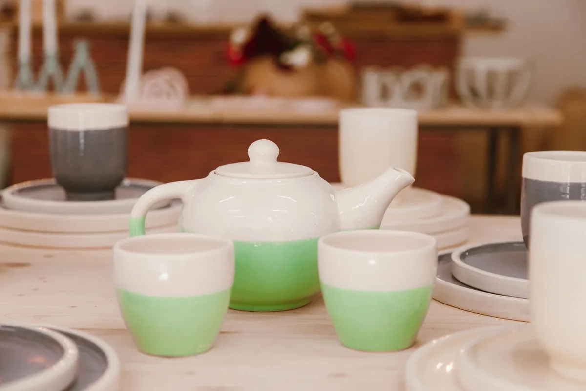 A teapot and several cups set out on a wooden table