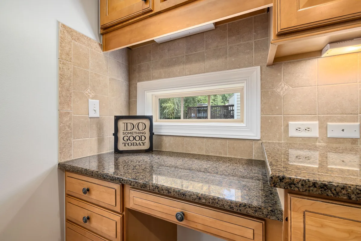 A tiled kitchen counter with wall outlets beneath a window