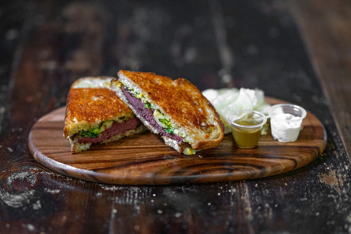 A toasted sandwich cut in half on a wooden board in a bright kitchen