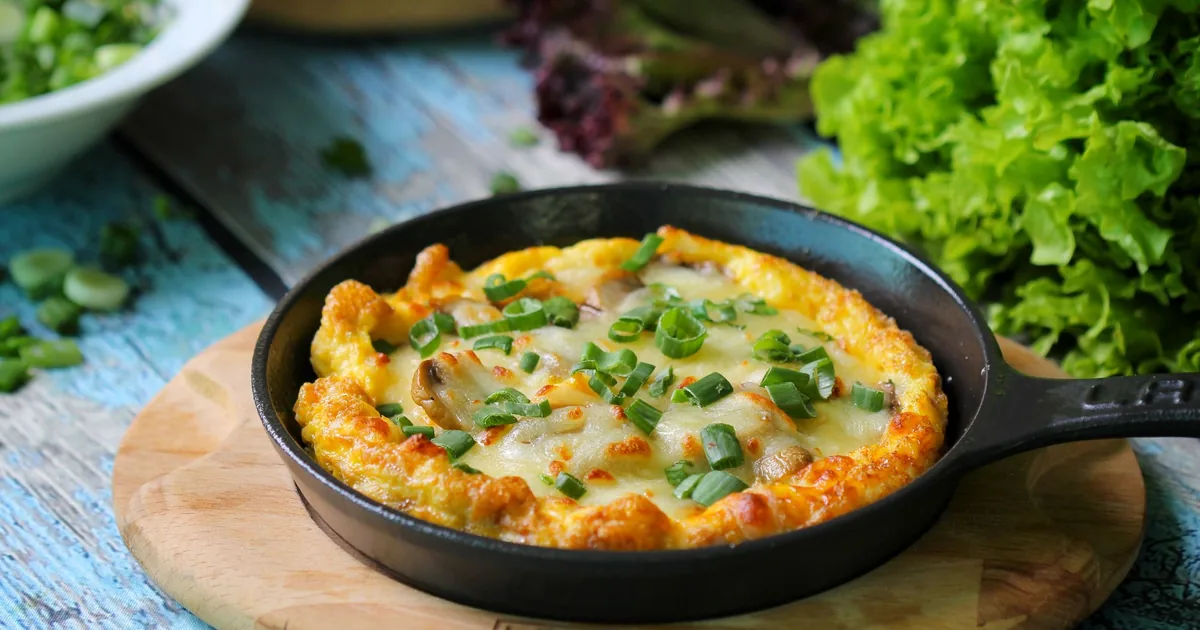 A vegetable frittata in a skillet on a wooden board