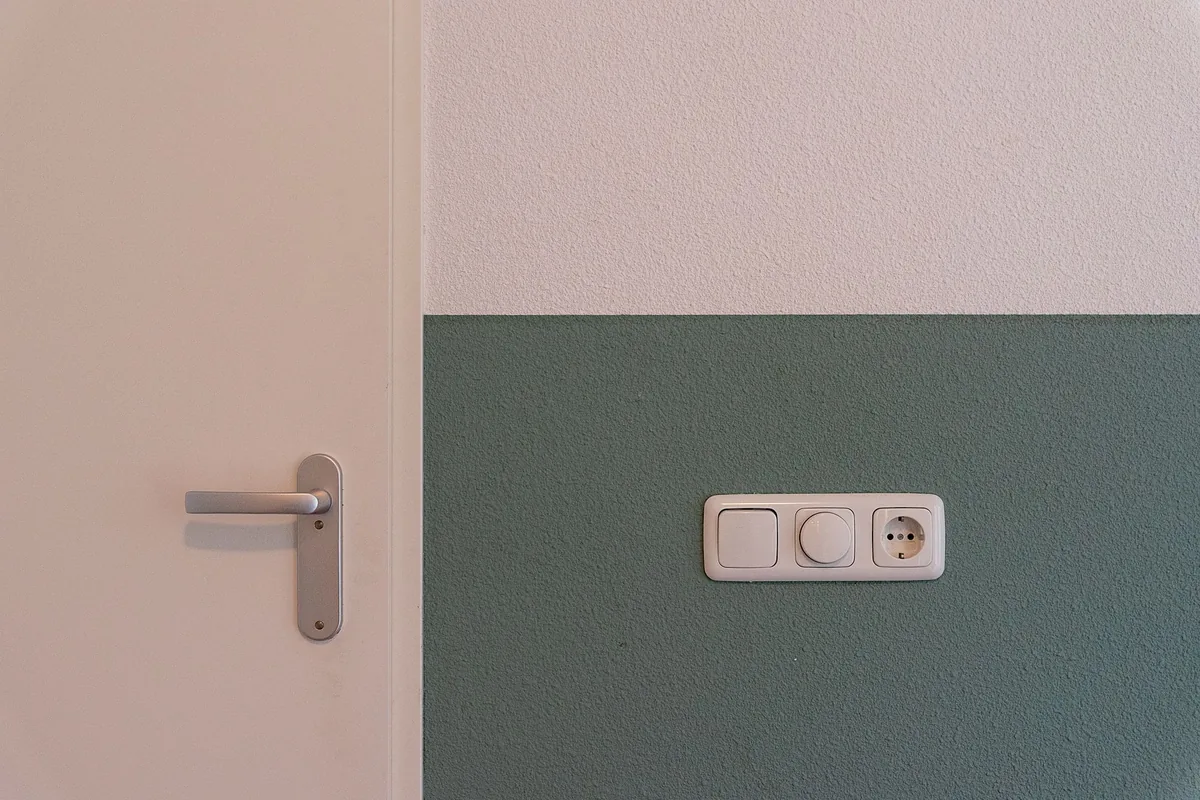 A wall outlet beside a door on a two-tone wall
