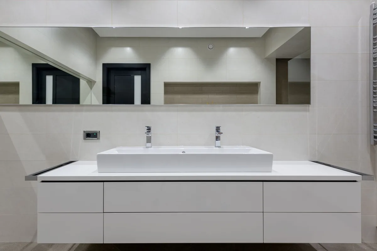 A white bathroom vanity with a basin and closed cabinet doors below