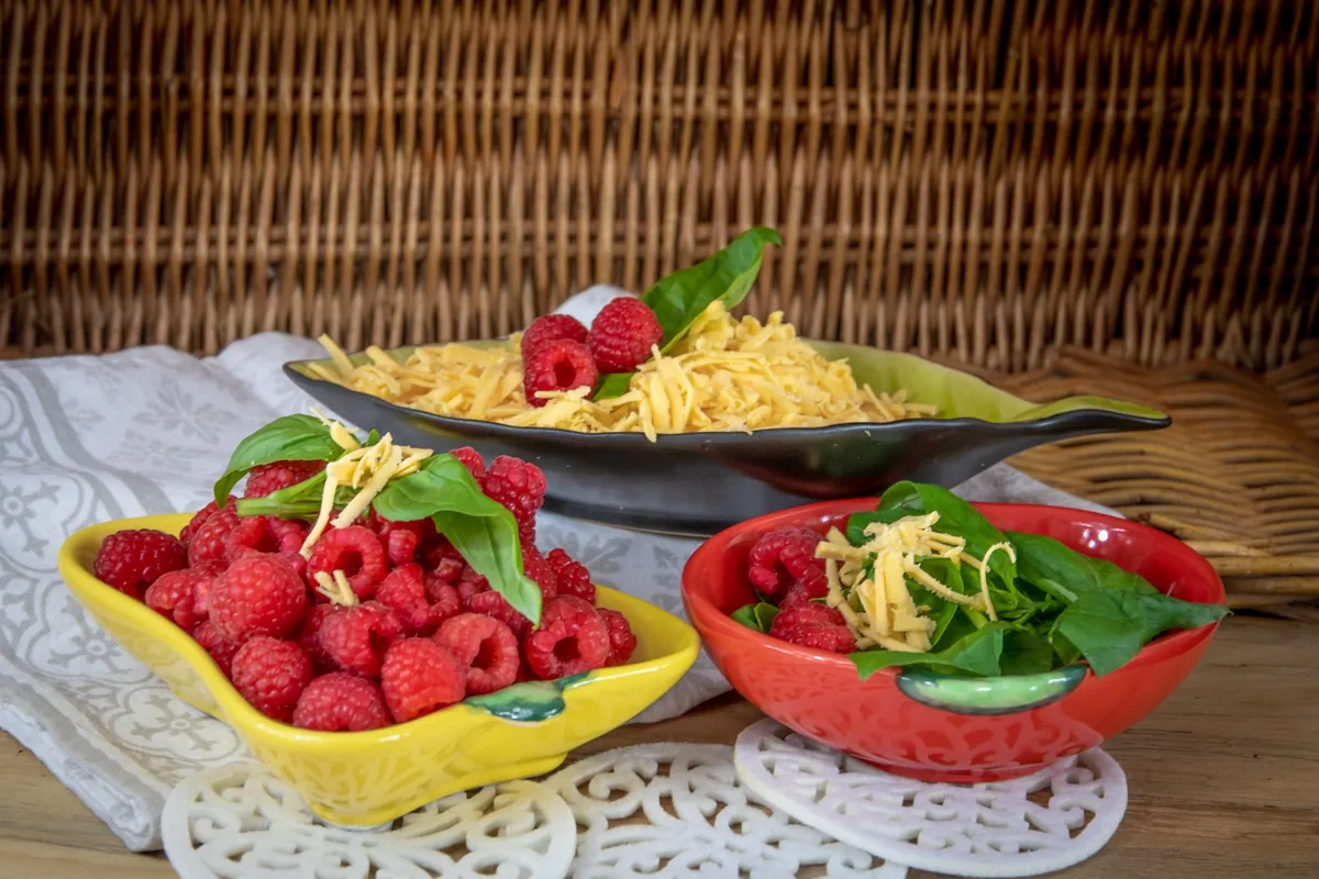 A white bowl filled with freshly grated yellow cheese on a light kitchen counter