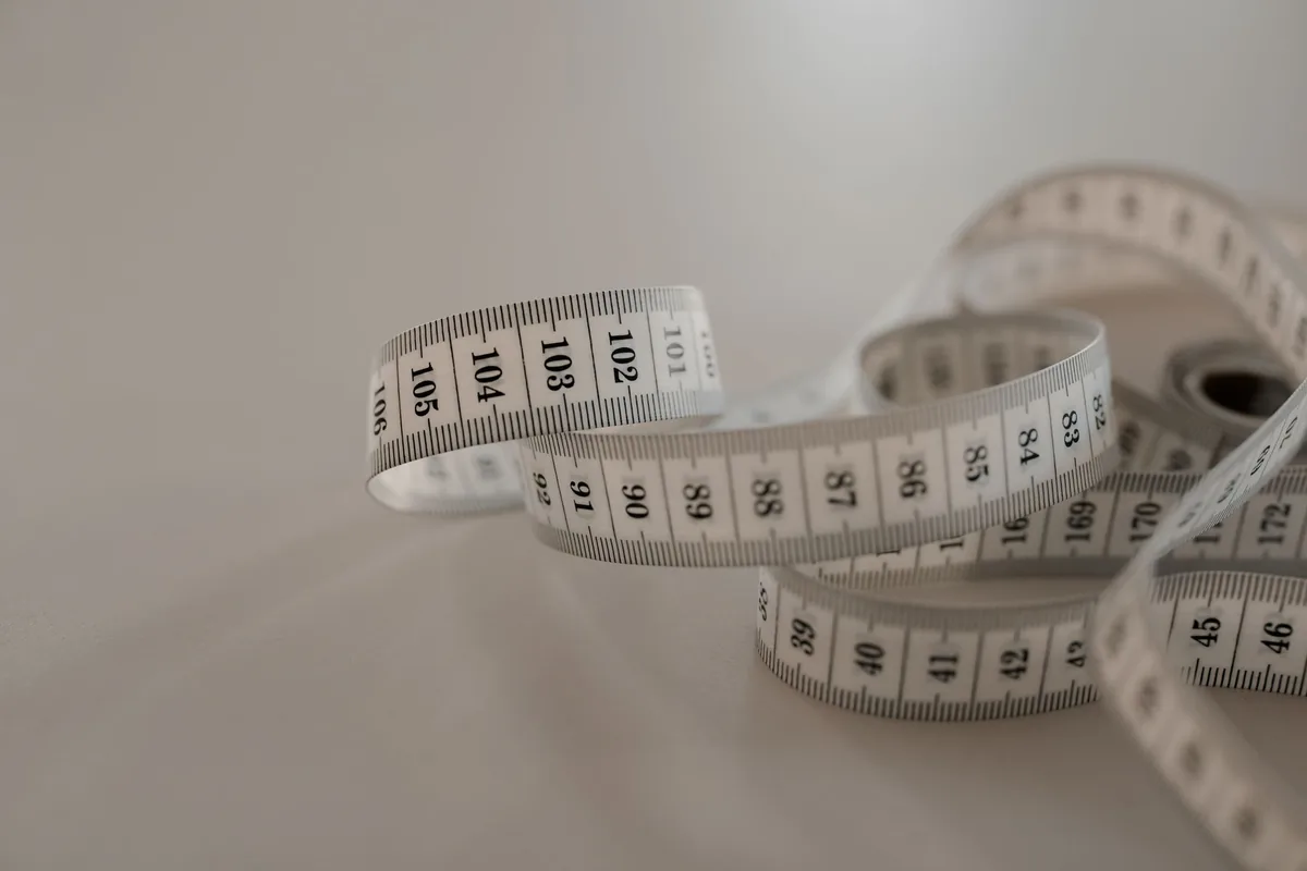 A white cloth tape measure curled on a light surface
